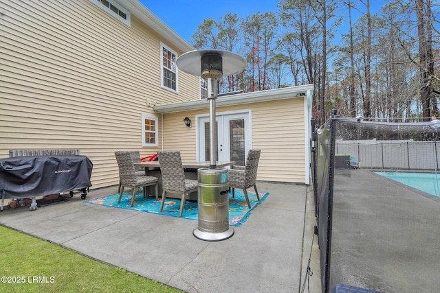 view of patio / terrace with a grill, french doors, a fenced in pool, and fence