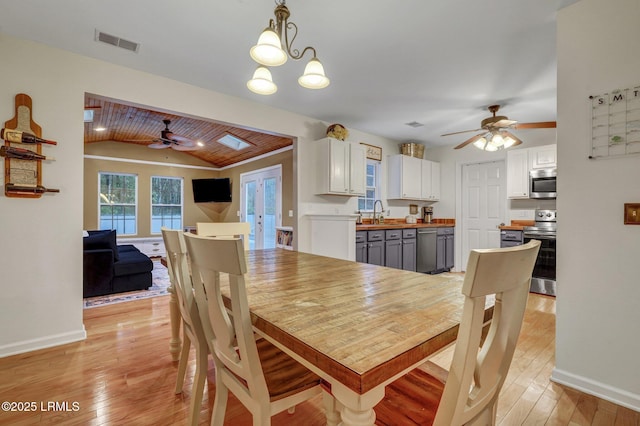 dining room with visible vents, baseboards, light wood-style floors, and lofted ceiling