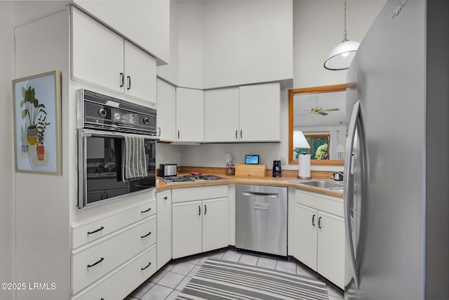 kitchen with a sink, white cabinetry, stainless steel appliances, a high ceiling, and light countertops