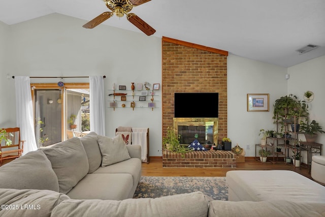 living room with wood finished floors, visible vents, a ceiling fan, lofted ceiling, and a fireplace