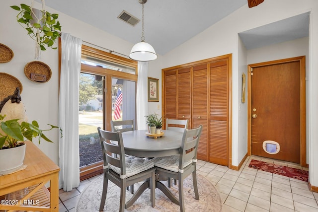 dining room with light tile patterned floors, visible vents, baseboards, and vaulted ceiling