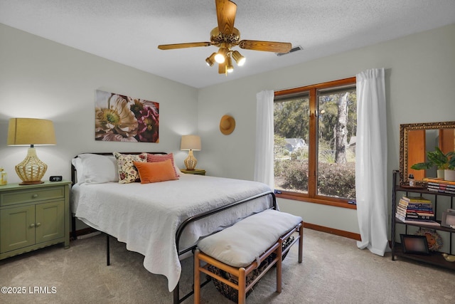 bedroom featuring visible vents, light carpet, a textured ceiling, baseboards, and ceiling fan