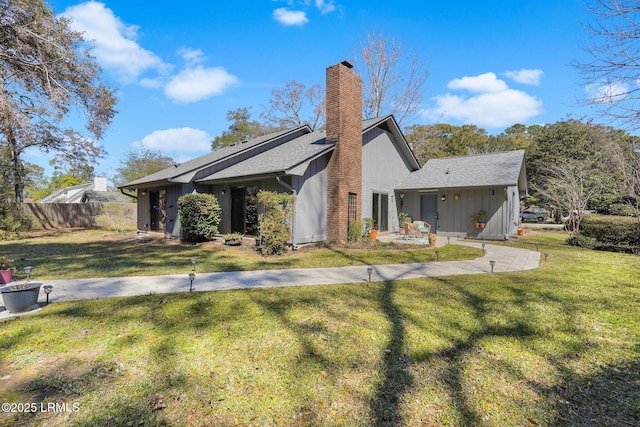 back of property featuring a shingled roof, fence, a chimney, a yard, and a patio