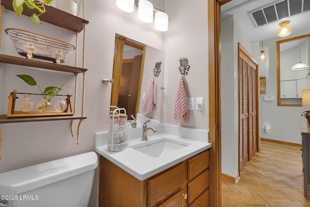 bathroom featuring visible vents, baseboards, toilet, and vanity