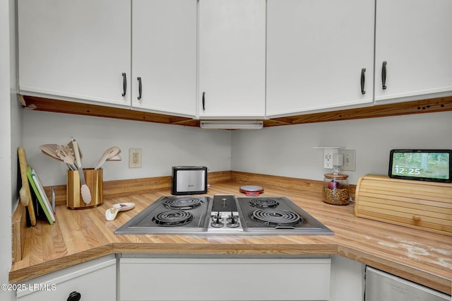 kitchen with white cabinetry, stainless steel electric stovetop, and wood counters