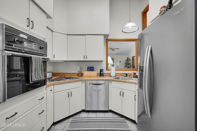 kitchen with a high ceiling, a sink, stainless steel appliances, light countertops, and white cabinetry