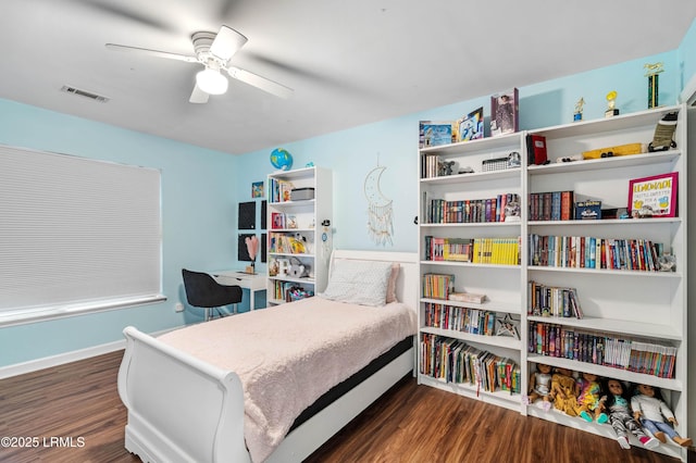 bedroom with a ceiling fan, visible vents, baseboards, and wood finished floors