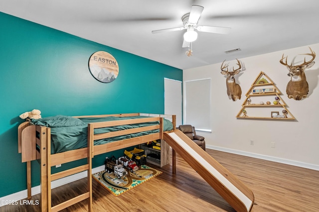 bedroom featuring visible vents, ceiling fan, baseboards, and wood finished floors