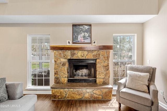 living area with a stone fireplace and wood finished floors