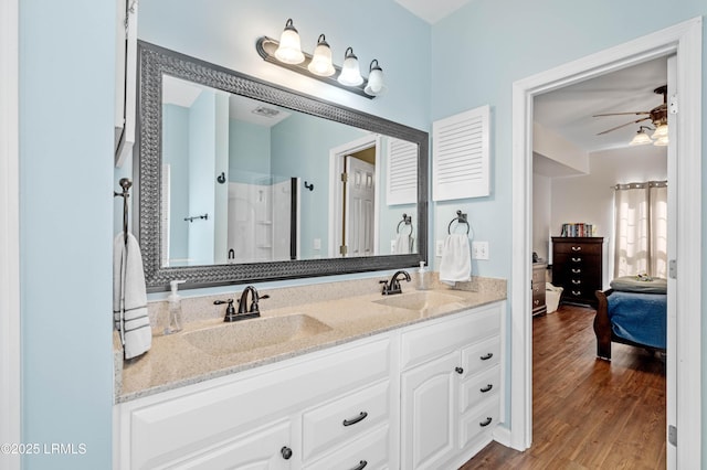 full bathroom with ceiling fan, connected bathroom, a sink, and wood finished floors