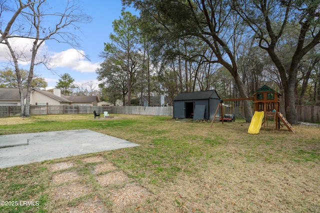 view of yard featuring a patio, a fenced backyard, an outbuilding, a shed, and a playground