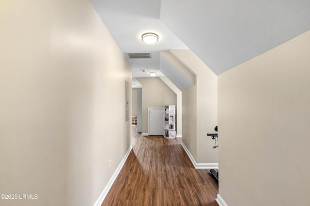 corridor featuring lofted ceiling, baseboards, visible vents, and wood finished floors