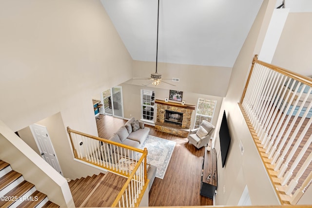 living room with a ceiling fan, a fireplace, high vaulted ceiling, and wood finished floors