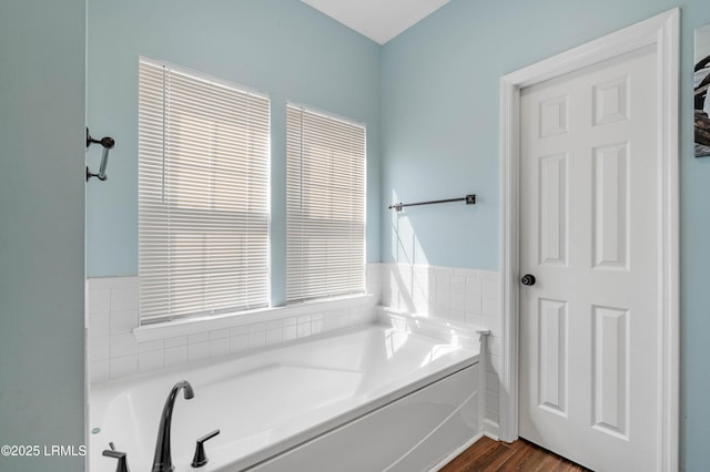 bathroom with wood finished floors and a garden tub