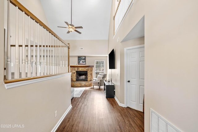 hall with high vaulted ceiling, dark wood-style flooring, visible vents, and baseboards