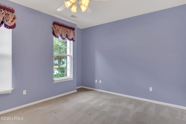 empty room with visible vents, baseboards, a ceiling fan, and light colored carpet