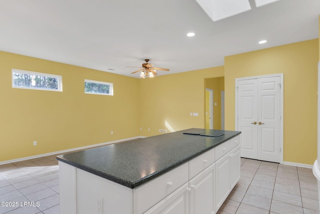 kitchen featuring dark countertops, white cabinets, a kitchen island, and light tile patterned floors