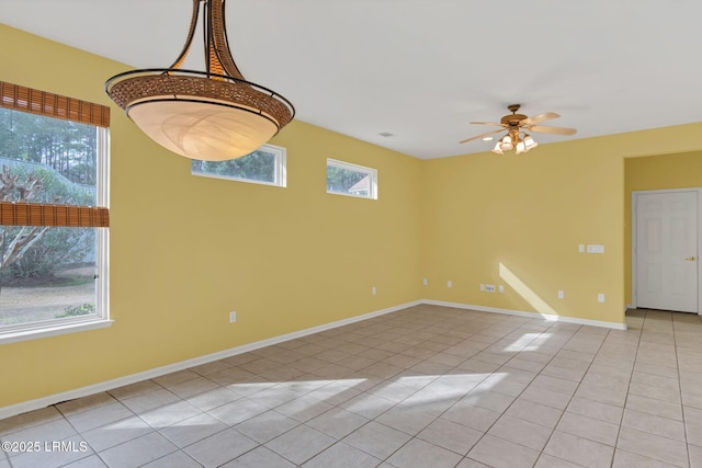 unfurnished room featuring a healthy amount of sunlight, light tile patterned floors, baseboards, and a ceiling fan