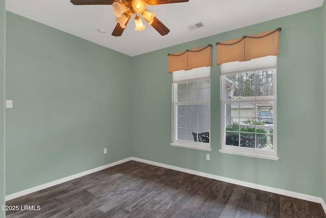 spare room with a ceiling fan, baseboards, visible vents, and dark wood-type flooring