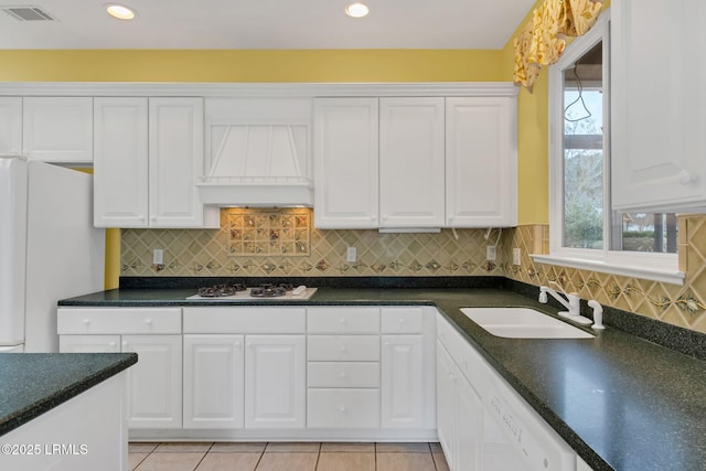 kitchen featuring dark countertops, white cabinetry, a sink, white appliances, and premium range hood