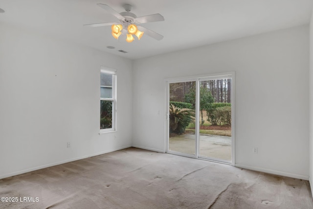 empty room featuring light carpet, ceiling fan, visible vents, and baseboards