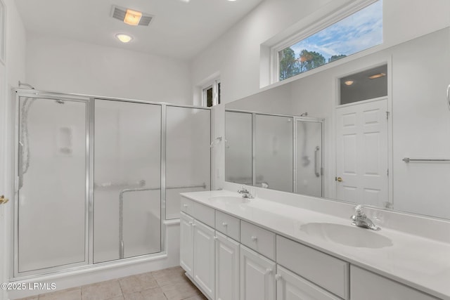 full bath featuring visible vents, a sink, a shower with door, and tile patterned floors