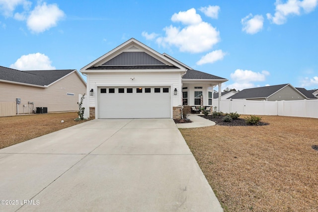 view of front of home with a garage, a front yard, central air condition unit, and a porch