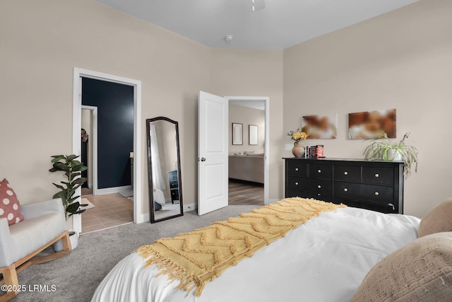 bedroom with ensuite bathroom and light colored carpet