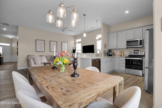 dining room with sink, ceiling fan, and light wood-type flooring