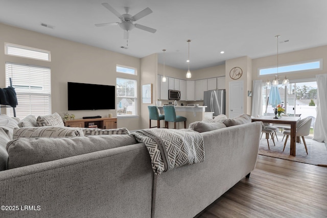 living room featuring hardwood / wood-style floors and ceiling fan with notable chandelier