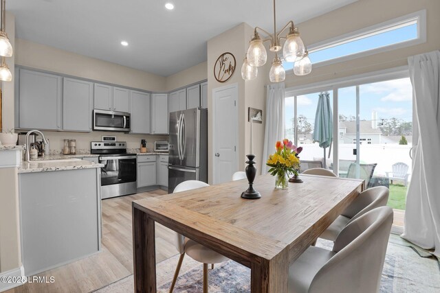 kitchen featuring hanging light fixtures, light stone countertops, appliances with stainless steel finishes, and gray cabinets