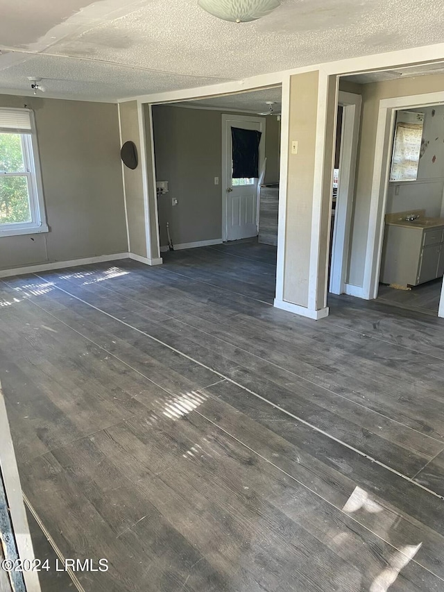 unfurnished living room featuring dark wood-type flooring and a textured ceiling