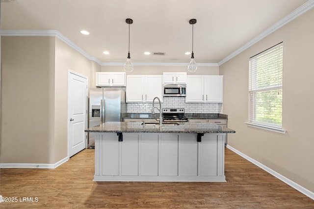 4944 Tidal Walk Ln, Beaufort, SC 29907 - kitchen with stainless steel appliances, a kitchen island with sink, tasteful backsplash, dark stone counters, and ornamental molding