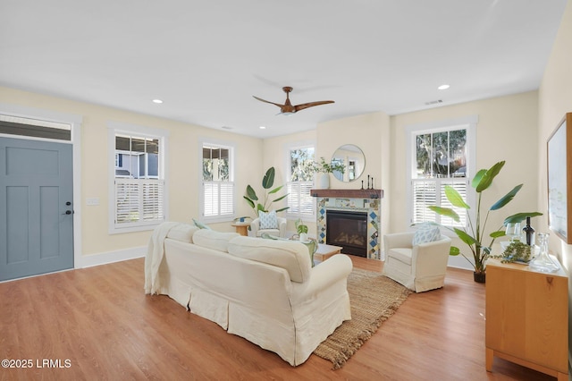 living area with a tile fireplace, visible vents, light wood finished floors, and recessed lighting