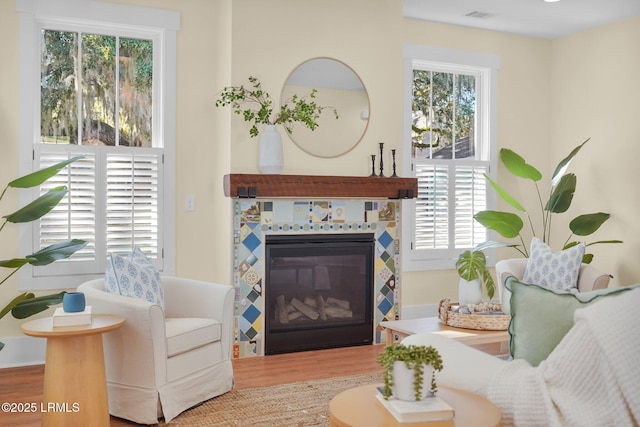 sitting room featuring a tile fireplace, visible vents, and wood finished floors