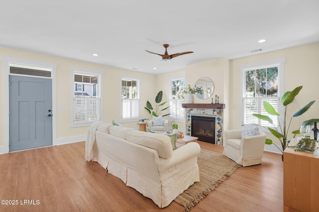 living area with visible vents, baseboards, a tile fireplace, light wood-type flooring, and recessed lighting