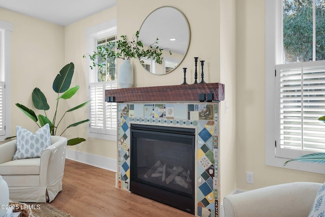 living area with a healthy amount of sunlight, a fireplace, baseboards, and wood finished floors