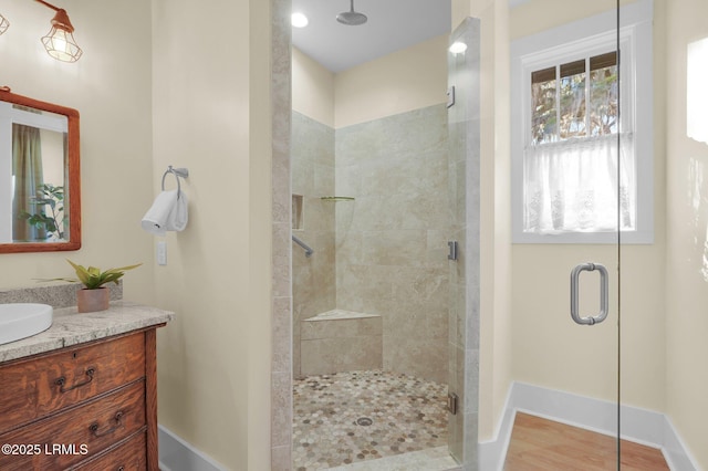 full bathroom with wood finished floors, a shower stall, baseboards, and vanity