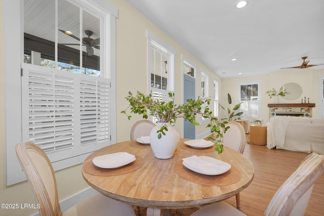 dining space featuring a ceiling fan, light wood-style floors, a fireplace, and recessed lighting