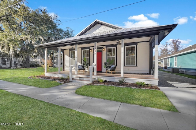 view of front facade featuring a porch, a front yard, a standing seam roof, ceiling fan, and metal roof