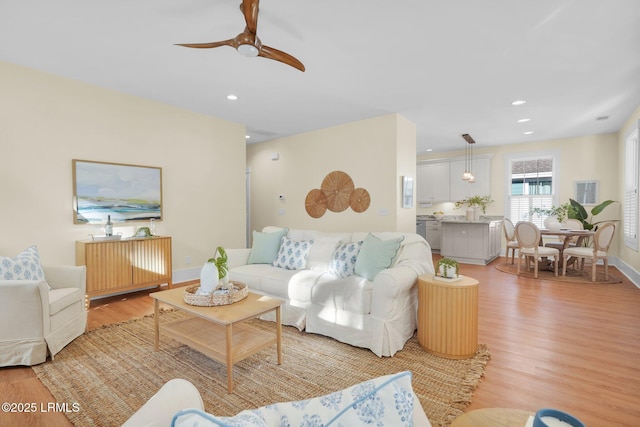 living room featuring a ceiling fan, light wood-type flooring, baseboards, and recessed lighting