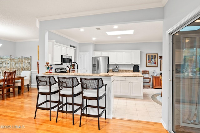 kitchen featuring white cabinetry, appliances with stainless steel finishes, crown molding, and light hardwood / wood-style flooring