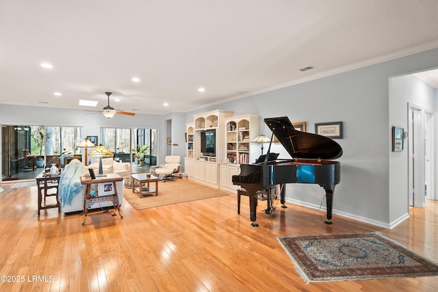 living room with crown molding, ceiling fan, and light wood-type flooring