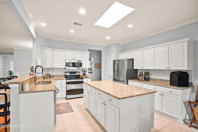 kitchen featuring a kitchen island, appliances with stainless steel finishes, sink, white cabinets, and a kitchen bar