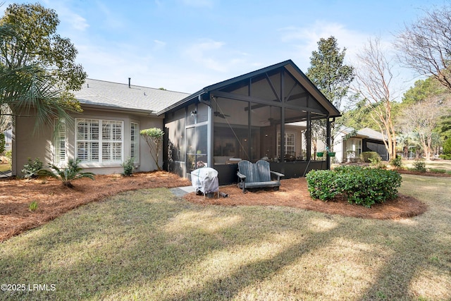 back of property with ceiling fan and a yard