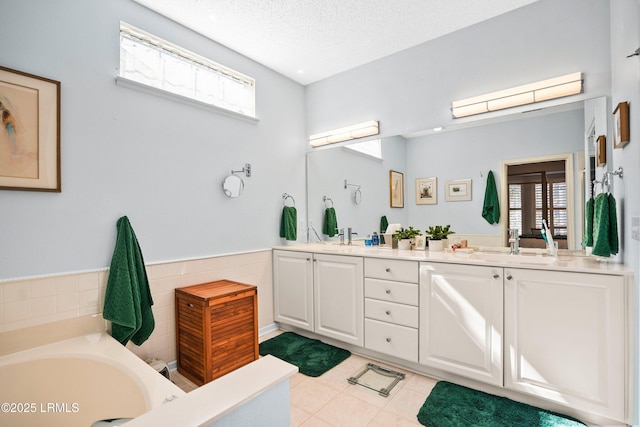 bathroom featuring vanity, a washtub, tile walls, and a textured ceiling