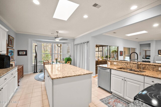 kitchen featuring sink, light stone counters, a center island, stainless steel dishwasher, and white cabinets