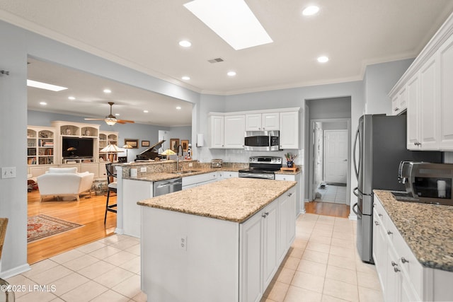 kitchen with white cabinetry, a kitchen breakfast bar, stainless steel appliances, a kitchen island, and kitchen peninsula