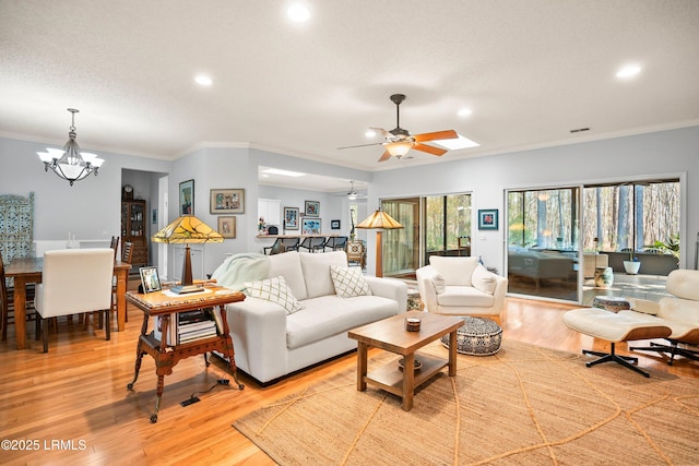 living room with ornamental molding, ceiling fan with notable chandelier, a textured ceiling, and light wood-type flooring