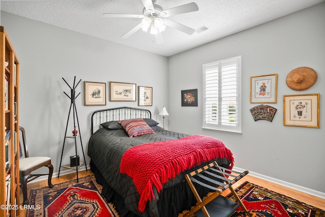 bedroom featuring hardwood / wood-style flooring, ceiling fan, and a textured ceiling